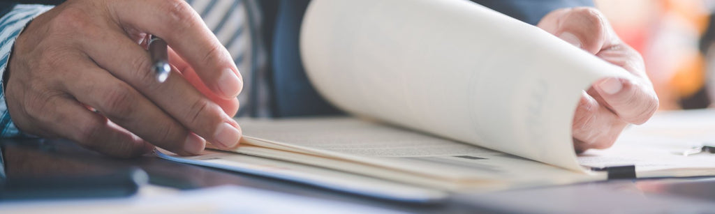 Hand paging through contracts while holding a pen
