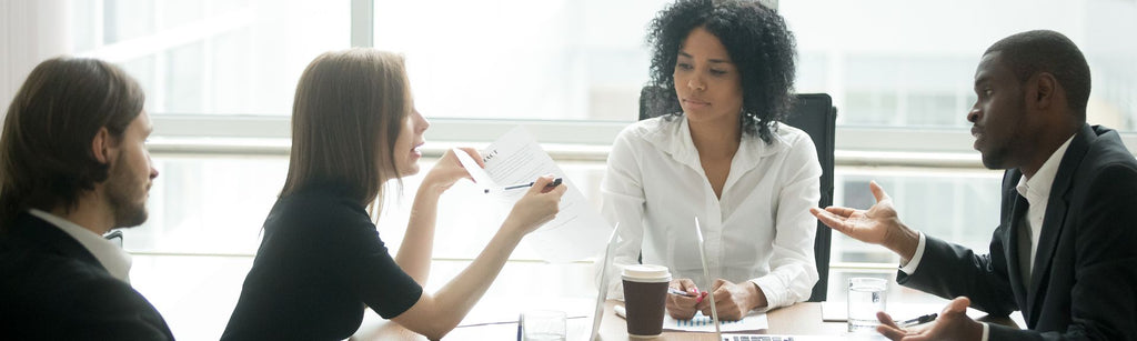 Group of diverse people, two women and two men, engaged in a dispute in a conference room